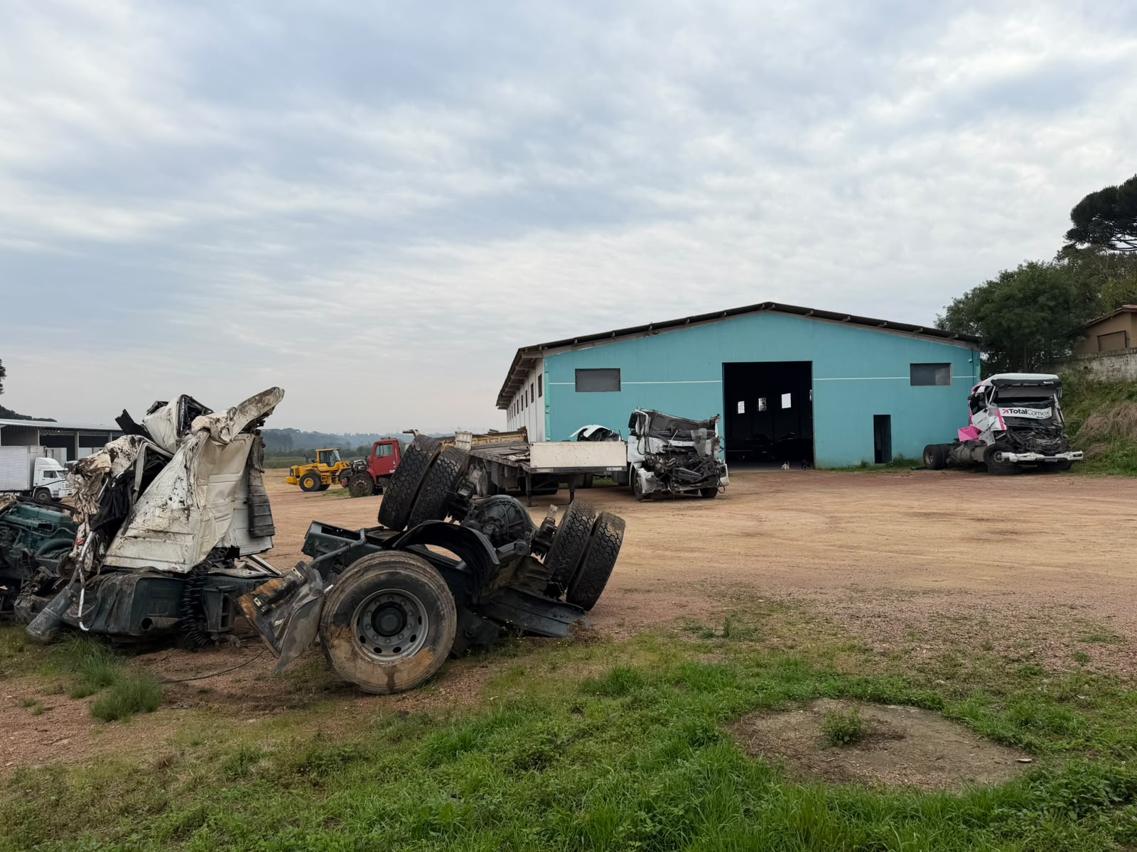 Pátio da N2 com chassi sinistrado e galpão ao fundo